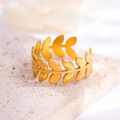 A 24K gold-plated adjustable ring featuring a delicate laurel leaf design. The band is crafted to resemble a wreath of small, intricately detailed leaves that wrap around the finger. The ring has an open-ended structure, allowing for a comfortable and flexible fit. The polished gold finish highlights the texture of the leaves, giving it a timeless and elegant appearance, inspired by ancient Greek victory wreaths.