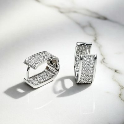 Silver pavé rectangular huggie earrings with sparkling clear stones and click closure, shown in a three-quarter view on a white background.
